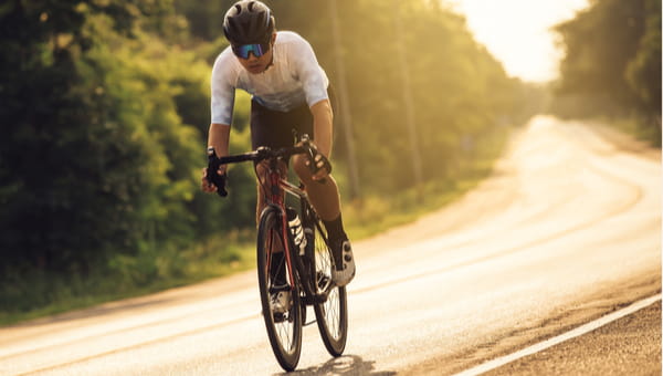Asian man Cyclist riding a bike on an open road to the sunset