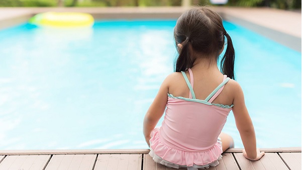 Little girl sitting on the edge of a pool