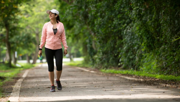 Relax Asian woman in sport cloth walking on the road at park