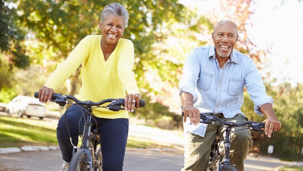 A senior couple is riding their bicycles in their neighborhood.