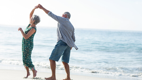 A senior couple is dancing on the beach.