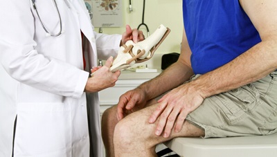 A doctor is examining a male patient's knees.
