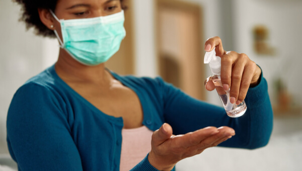 a woman wearing a mask and putting sanitizer on her hands