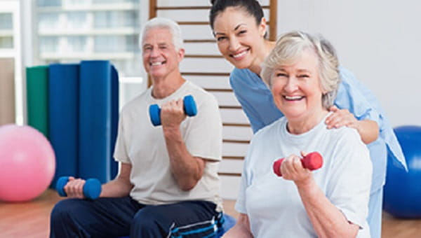 an older man and woman lifting dumbbells