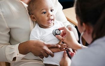 A doctor is checking the heartbeat of a baby during a visit.