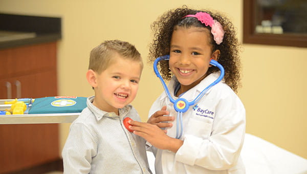 Girl pretending to examine young boy