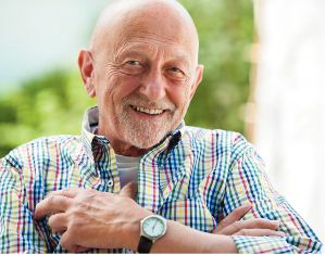 Older man smiling in a checkerd shirt with a wrist watch