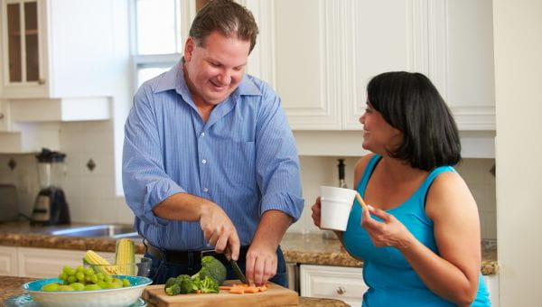 Overweight Couple On Diet Preparing Vegetables In Kitchen