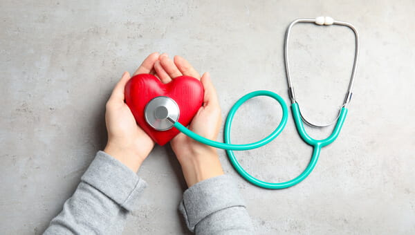 Hands holding a heart with a stethoscope on it