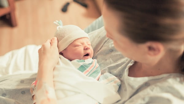 A mother cradles her newborn in the hospital room.