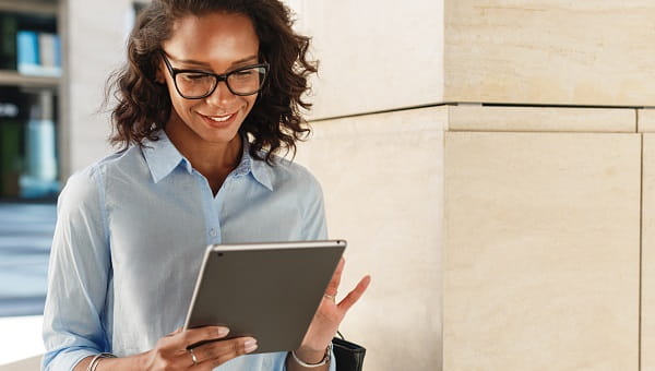 A woman smiling while holding her smart tablet device