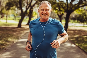 A senior man is jogging in a park.