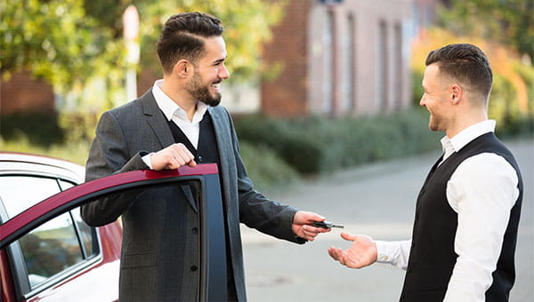 A male driver gives his car key to a valet