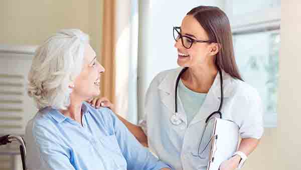 Female healthcare provider talks with senior female patient.