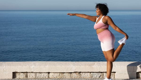 A woman doing yoga near the water