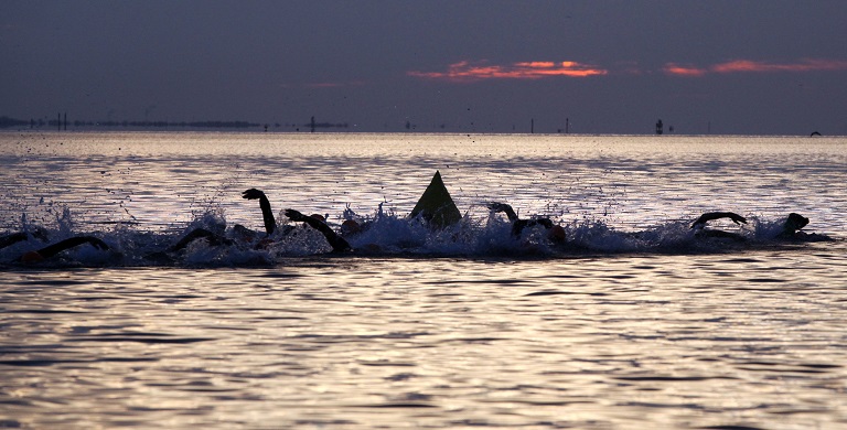 Swimmers at sunrise in Tampa Bay during the St. Anthony's Triathlon