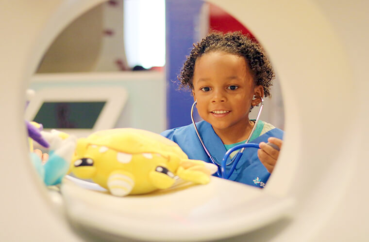 A child looks at a toy in a CT scanner