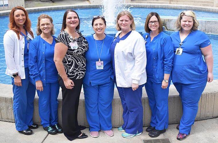 Seven medical staff standing in front of a fountain
