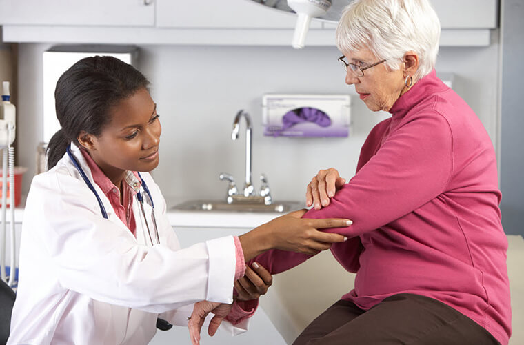 A doctor examines a senior woman's arm