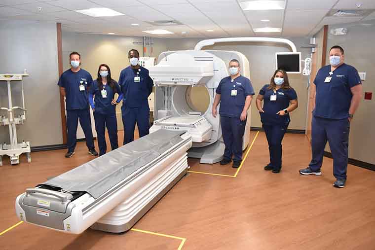 Imaging team members standing with the nuclear medicine camera