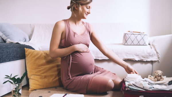 pregnant woman sitting on her couch holding her stomach