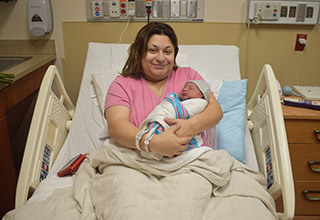 New mom Arlene smiles as she holds baby Leonardo in their hospital room.
