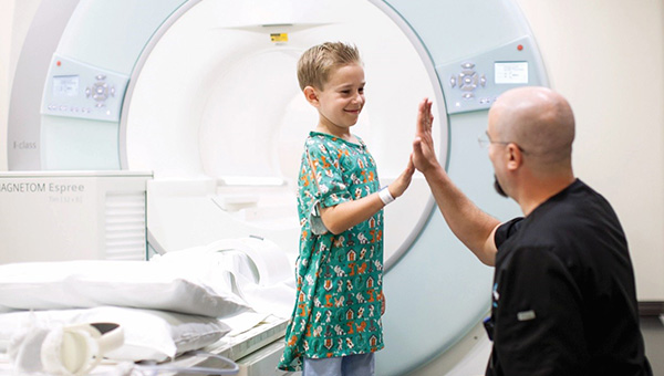 Child patient giving Radiologist a high five in front of an MRI machine