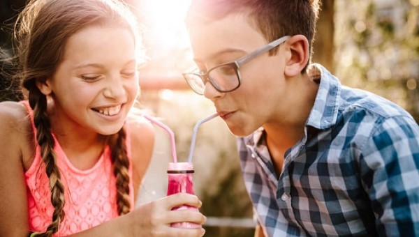 Boy and girl drinking from soda bottle