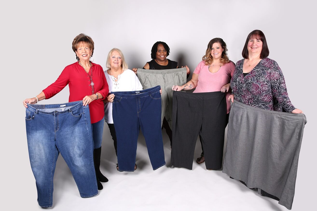 a line of women holding up their former pair of pants
