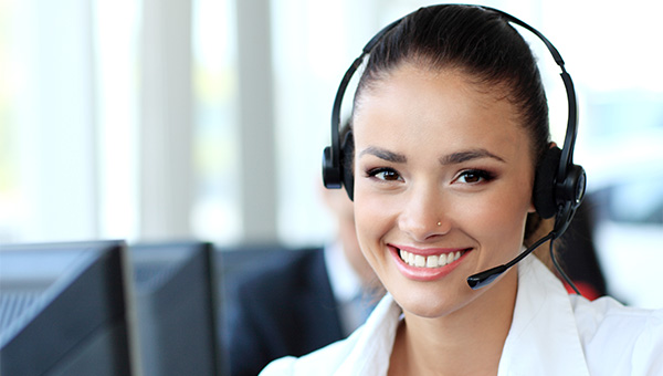 A smiling woman wears a headset while helping callers in the Customer Service Center.
