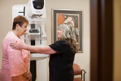 female patient and imaging technician preparing for a screening mammogram 