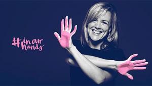 A smiling woman shows the palms of her hands, which are painted pink for the BayCare breast cancer awareness campaigned called In Our Hands.