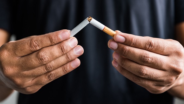 A man is quitting smoking and breaks a cigarette in half.