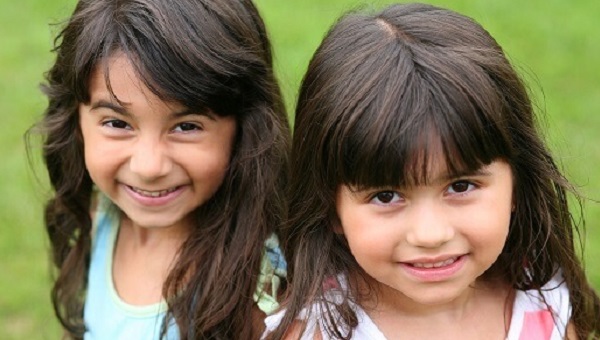 Two little girls are smiling outside.