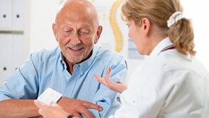 A female doctor talks with a senior male patient.