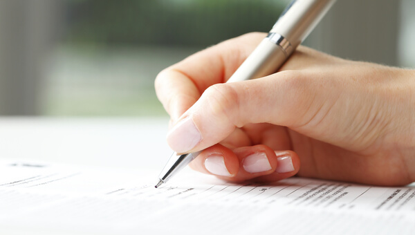 A woman is completing a form using a pen.