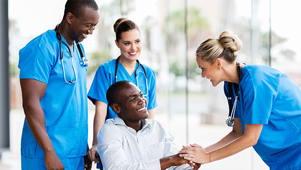 A smiling male patient talks with two female nurses and a male nurse