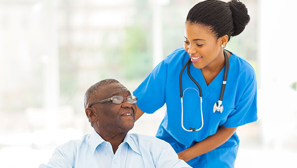 A smiling female nurse talking with a senior male patient.
