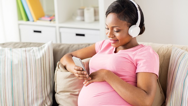 A young pregnant woman is listening to podcasts.