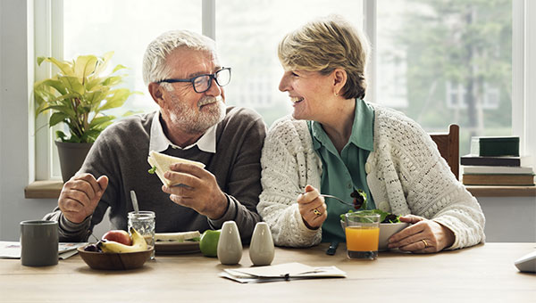 A senior couple is eating a meal together.