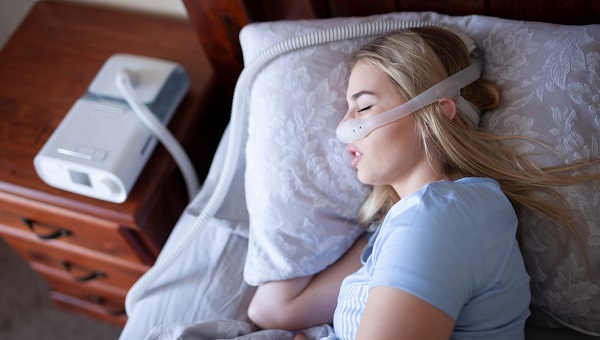 A woman is using a CPAP machine while sleeping.