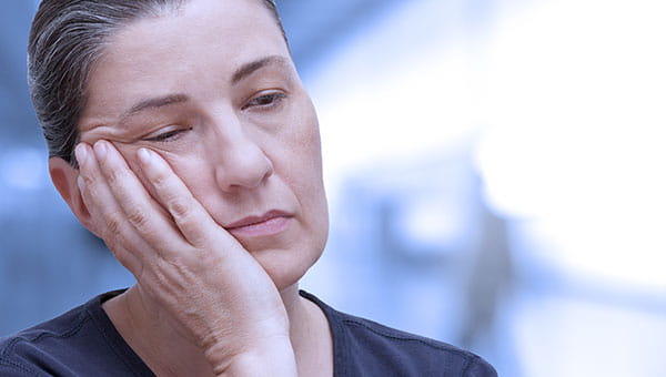 A woman looks tired and sleepy while resting her head on her hand. 