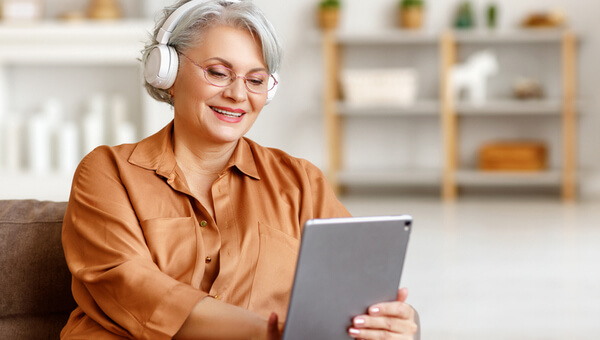 a woman with headphones sitting down with her tablet