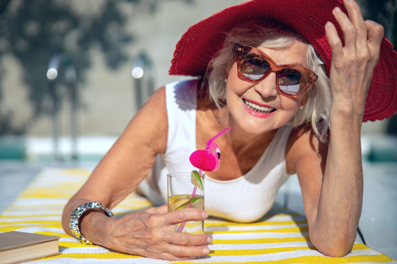 an older woman outside smiling with sunglasses and a sunhat