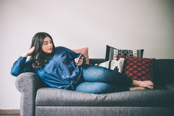 Woman lying on couch looking at her cell phone