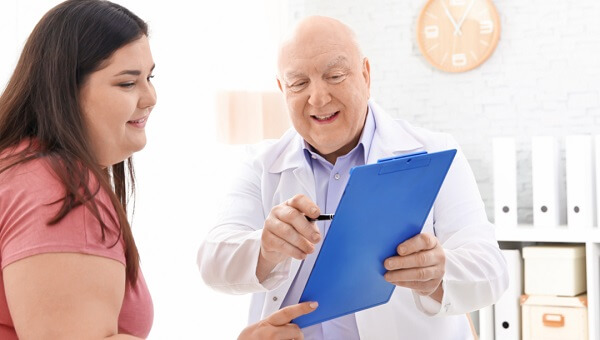 a doctor pointing at his clipboard with his smiling female patient