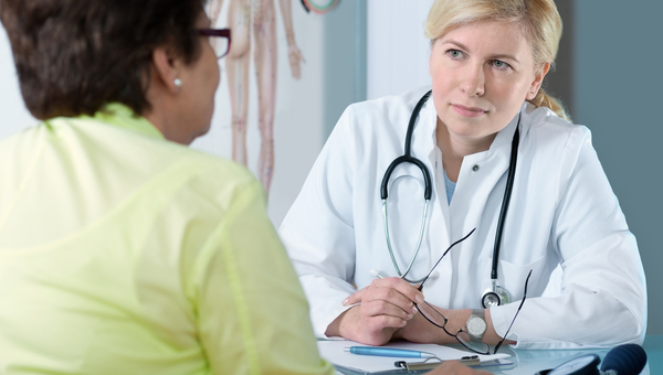 A senior woman talks with a female physician.