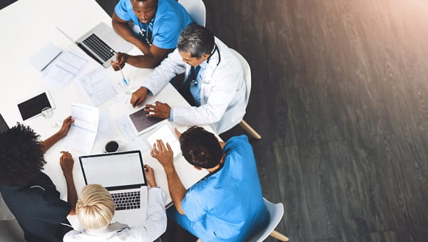 A top down photo of a clinical team looking through spreadsheets and on their laptops.