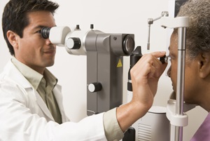 A male doctor examining the eyes of a senior female patient.