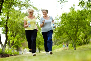 Two senior females are walking in a park.